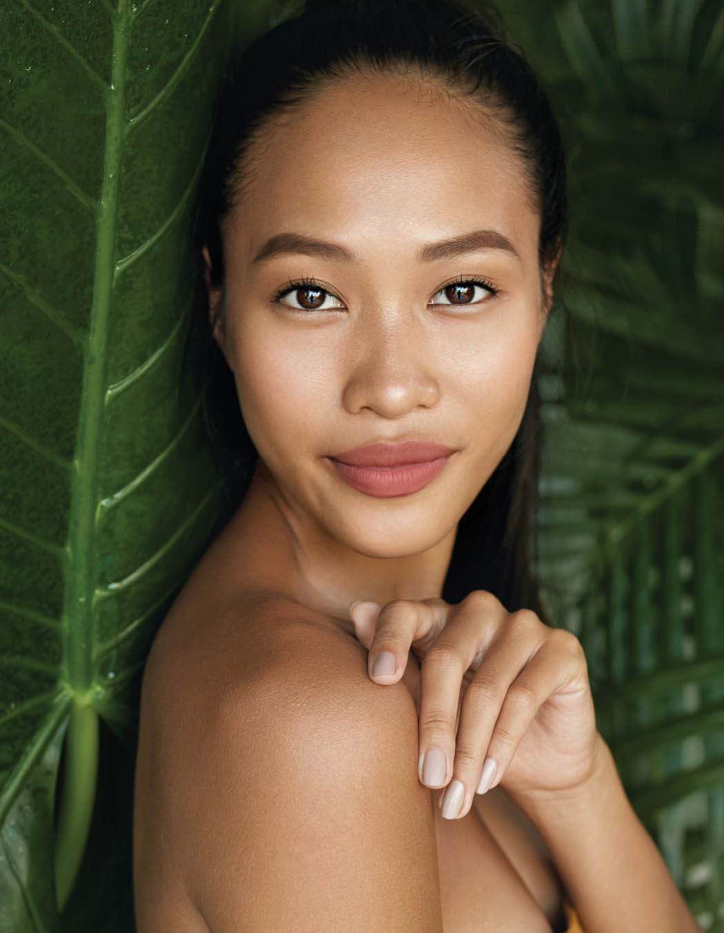 Beauty face  Woman model with natural makeup and healthy skin in tropical nature  Beautiful asian girl portrait with jungle leaves on background