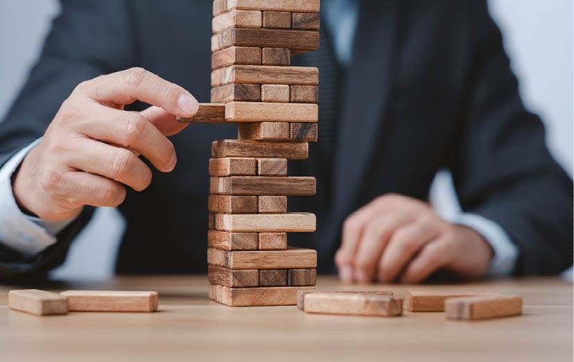 Planning, risk and strategy in business  Businessman holds the model of business, made from wood blocks  Alternative risk concept, business plan and business strategy  Insurance concept 
