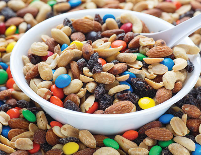 Colorful trail mix in a white bowl with spoon
