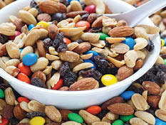 Colorful trail mix in a white bowl with spoon