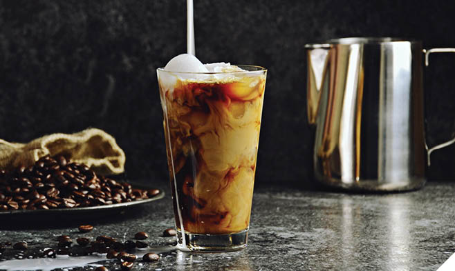 Iced coffee in a tall glass with cream poured over. Iced coffee isolated