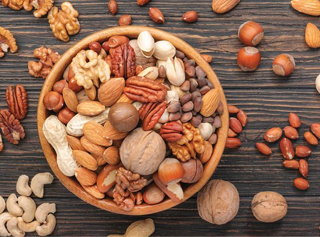Assortment of nuts in bowls. Cashews, hazelnuts, walnuts, pistachios, pecans, pine nuts, peanuts, macadamia, almonds, brazil nuts. Food mix on wooden background, top view, copy space