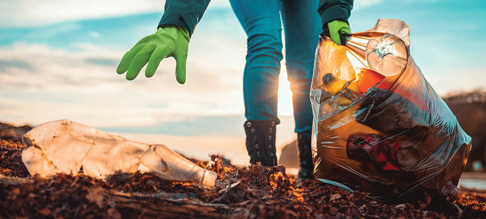 A volunteer collects garbage on a muddy beach. Close-up. The concept of Earth Day. Bottom view.