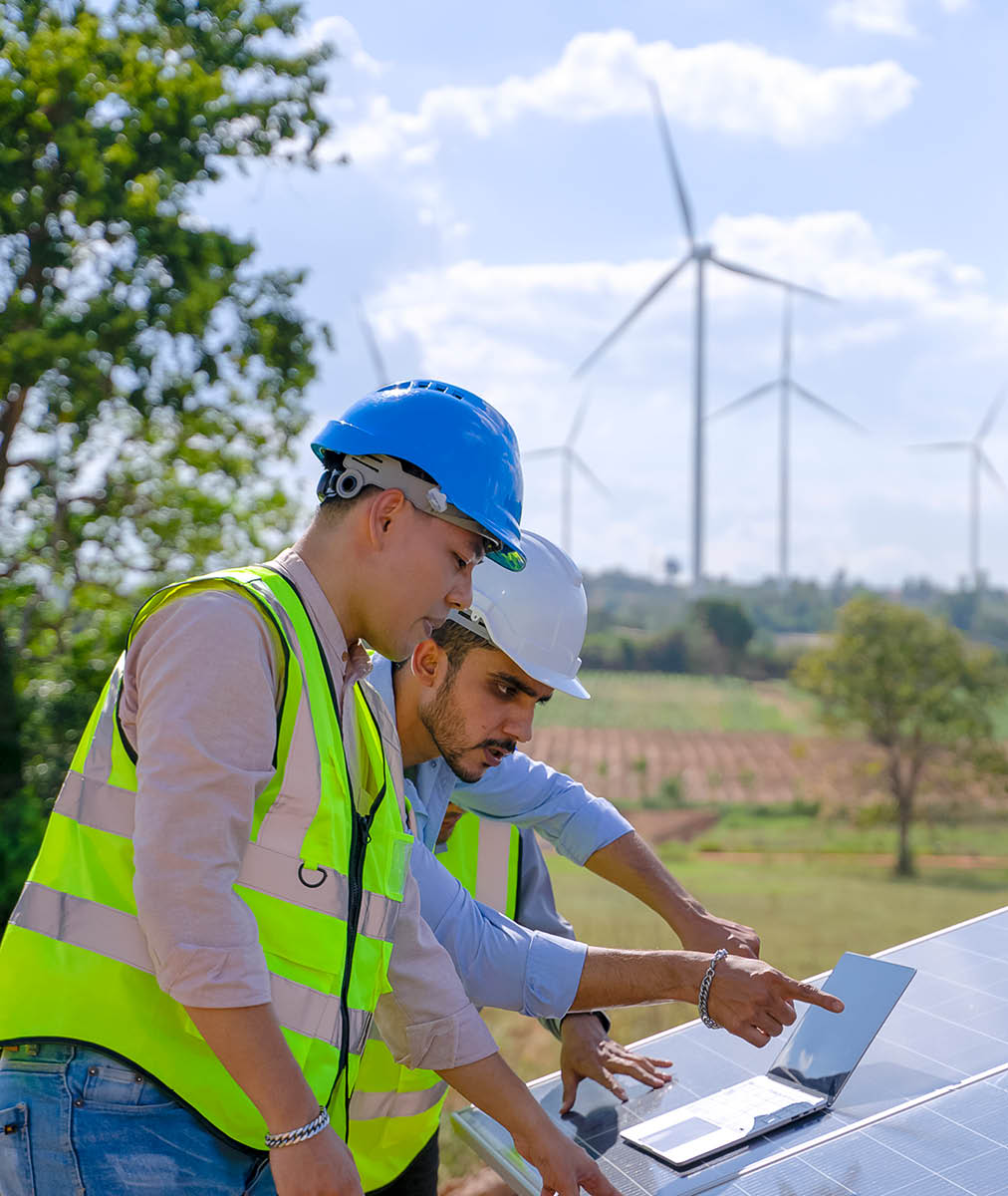 Blue collar workers at electricity site. Windmill field. They are working in the field during the day. Alternative energy.