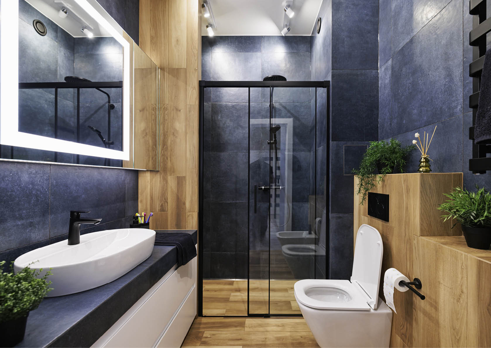 Modern, dark luxury bathroom with indigo and wood like tiles. Black rain shower head. Lacquered white drawers. Modern mirror with built-in led illumination. Canon R5.